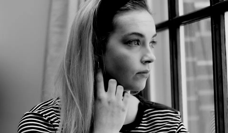 Mulher pensativa olhando pela janela